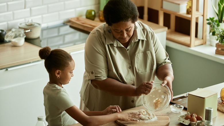 a woman and a child make dough together in kitchen