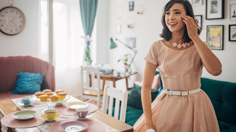 woman in old-fashioned dress sets table for party