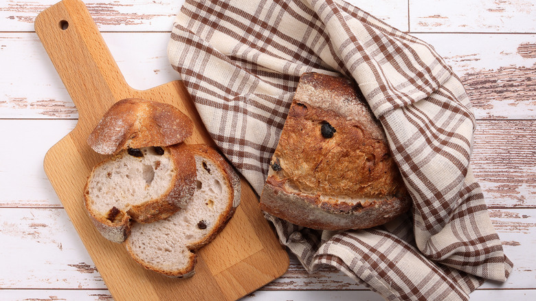 Bread wrapped in cloth with slices on wood cutting board