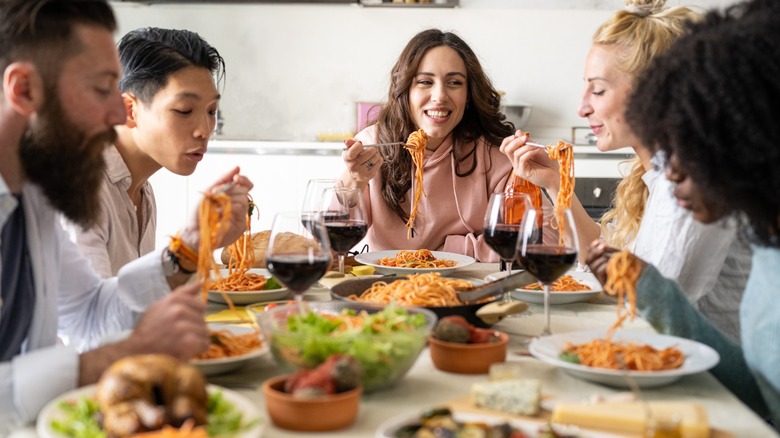 a table of friends eat pasta together