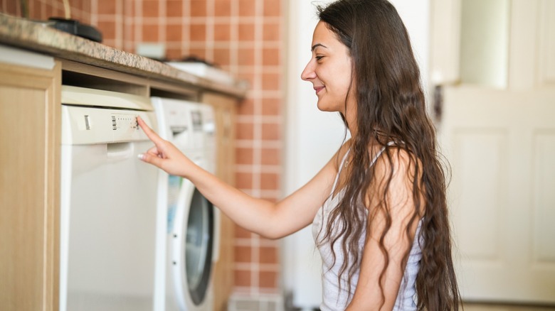 a woman sets the dishwasher in her kitchen