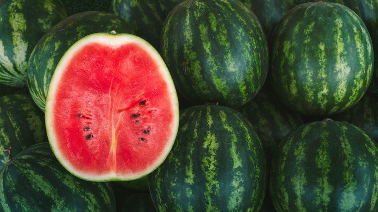 Red watermelon cross section with whole watermelons in the background 