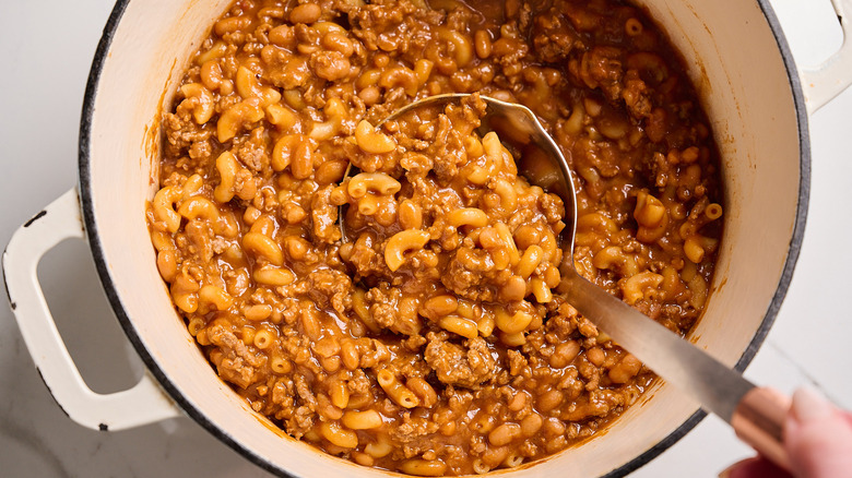 Baked bean chili mac in a pot with a ladle