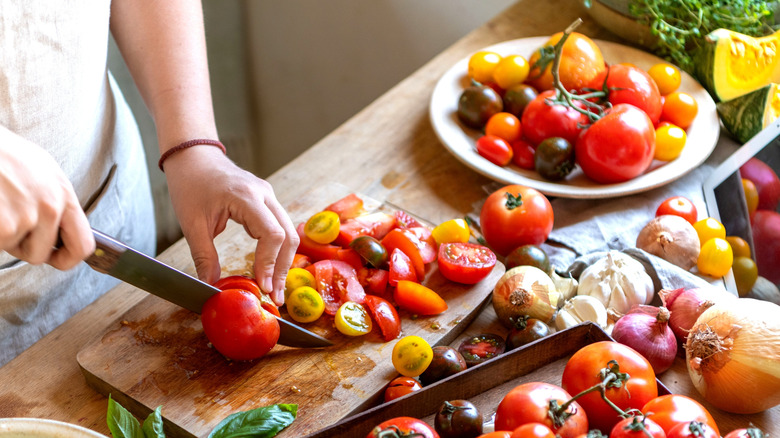 Someone chopping tomatoes on a wooden block