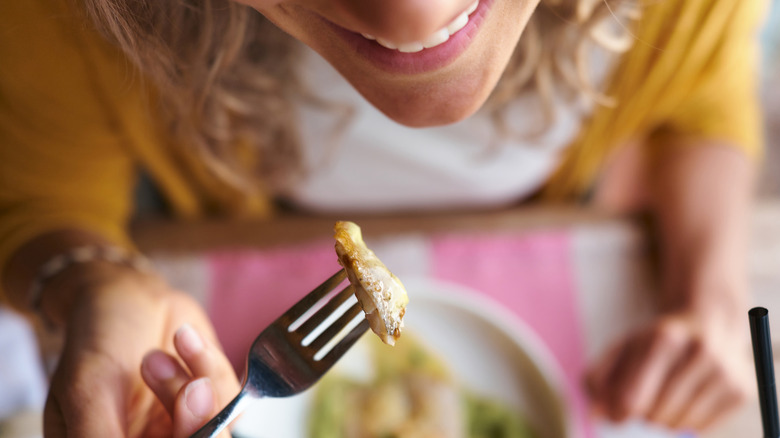 Closeup of person holding piece of fish on fork.