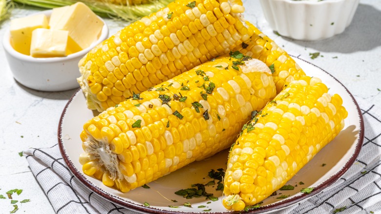 Boiled corn with herbs and cubes of butter on the side