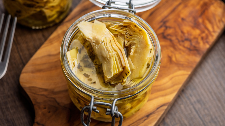Pickled artichoke in jar on a wooden table