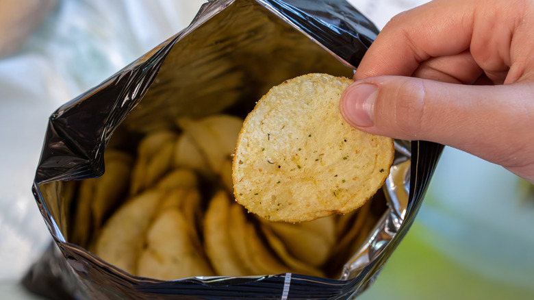 Someone taking a potato chip out of a bag