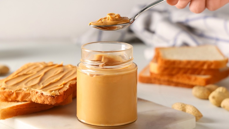 Person lifting spoonful of peanut butter from jar