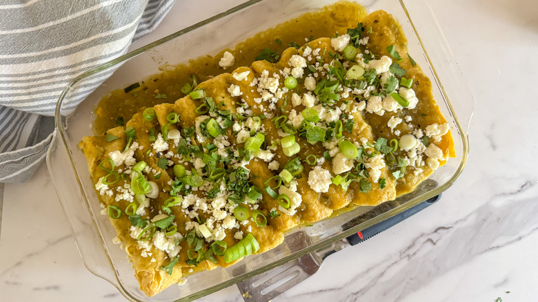 enchiladas verdes in pan topped with queso fresco and green onions