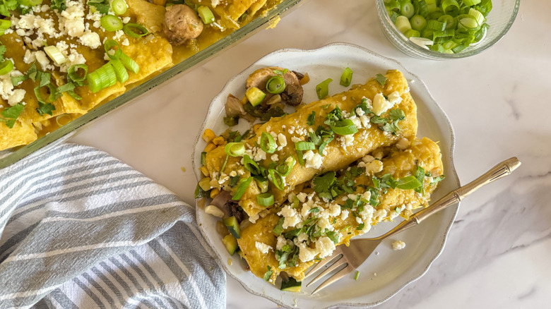 Enchiladas verdes on plate topped with queso fresco and green onions