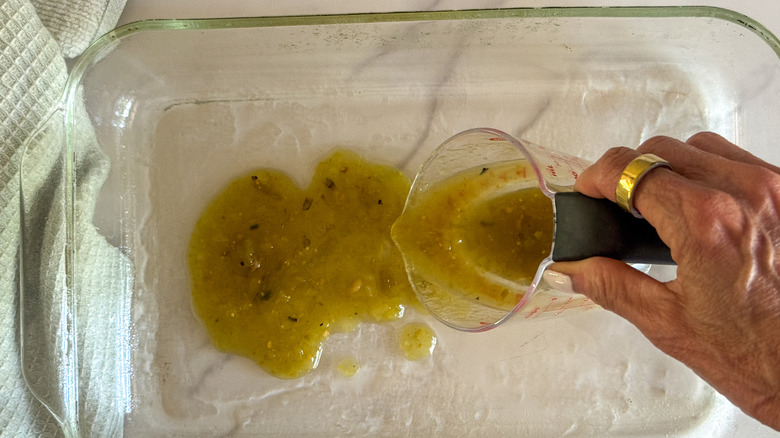 hand spreading salsa in baking dish