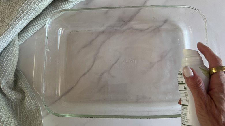 hand spraying baking dish
