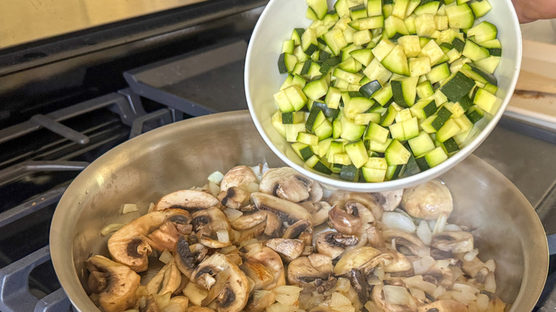 adding zucchini to pan with mushrooms
