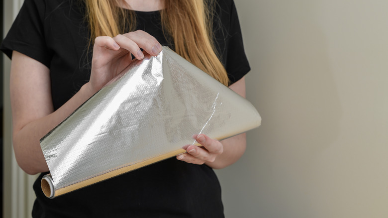 A woman unrolling aluminum foil