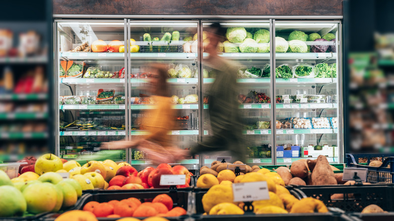 Blurred shot of customers pushing shopping cart through produce section
