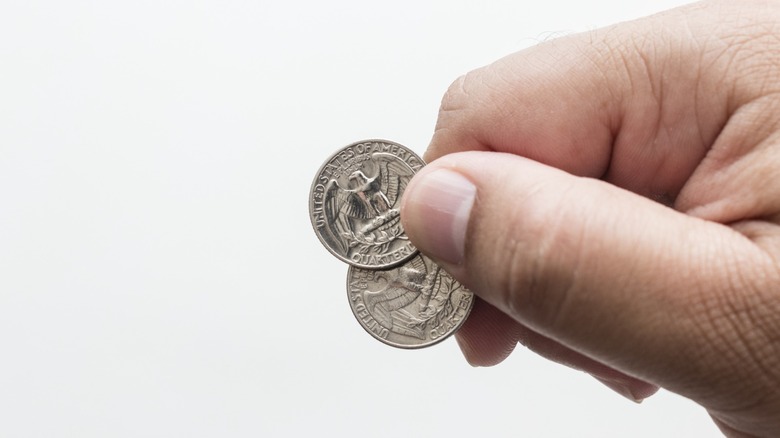hand holds two u.s. quarters