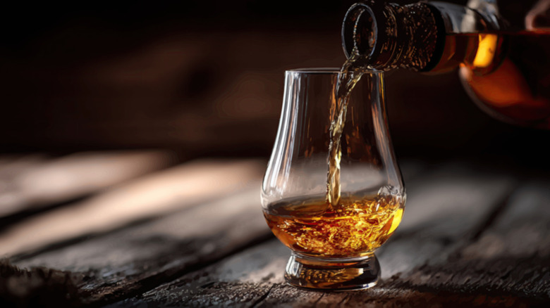 Close-up of whiskey poured from a bottle into a glass