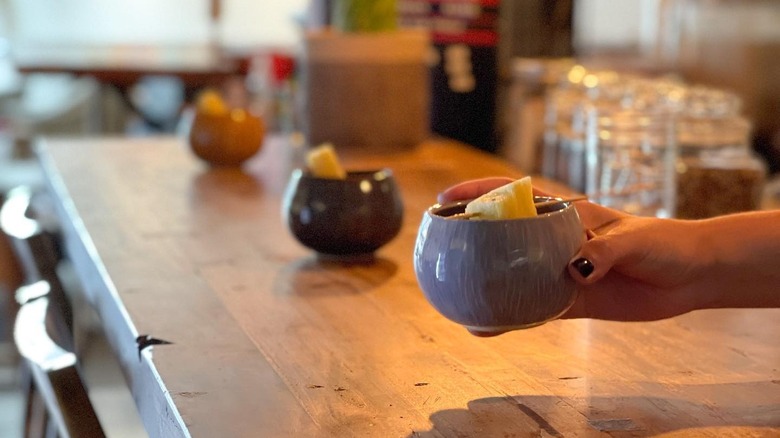 bartender handing a cup of kava across a bar