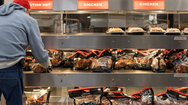 customer selects costco rotisserie chicken from hot case
