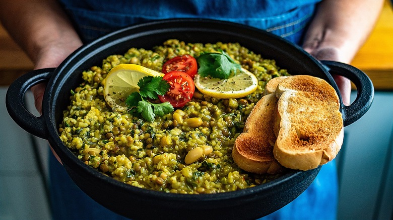 hands hold pan with high-fiber lentil and bean dish