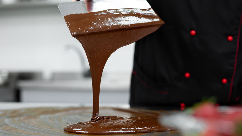 Pastry chef using a spatula to temper chocolate.