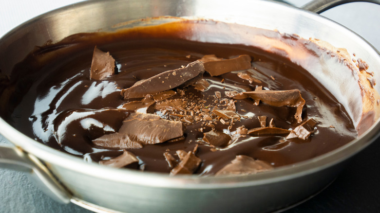 Mixing in seeds while tempering chocolate in a saucepan.