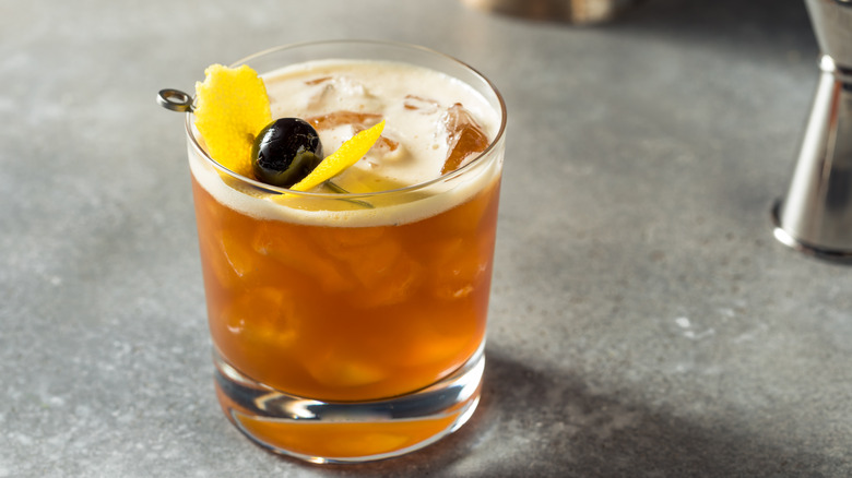 Small cocktail on ice with lemon peel and cherry. 