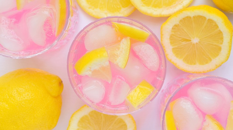 Glasses of pink lemonade with ice and lemons