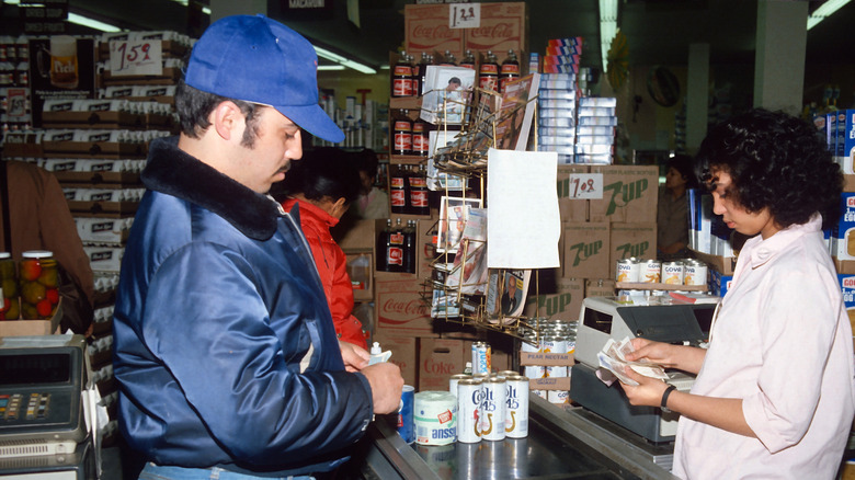 a man buys groceries with food stamps in the 1980s