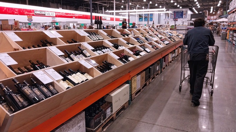 customer pushing cart in costco wine aisle
