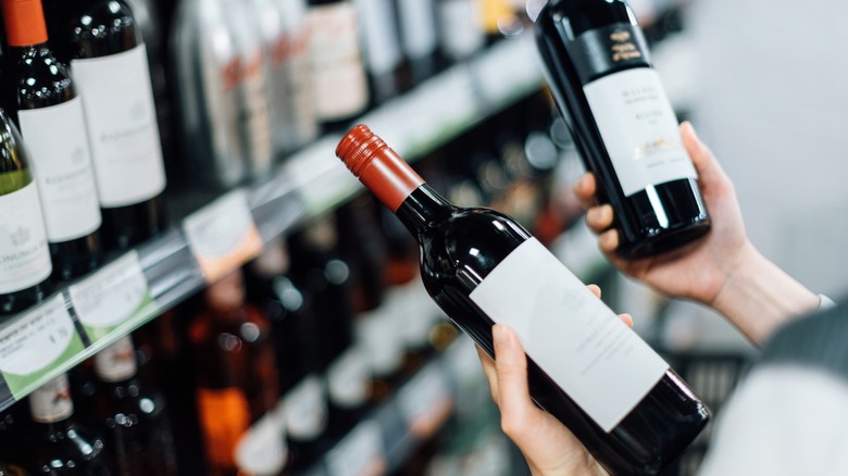 a person compares two bottles of wine