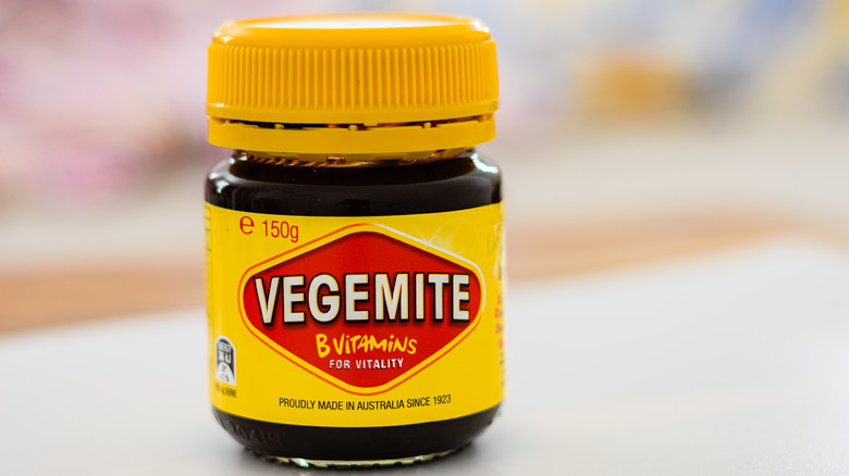 Small dark jar of Vegemite with a yellow and red label.