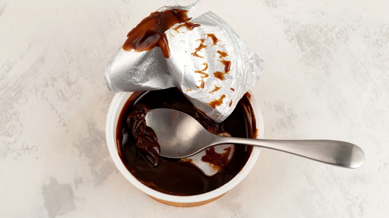 Plastic container of Vegemite spread with a spoon. 