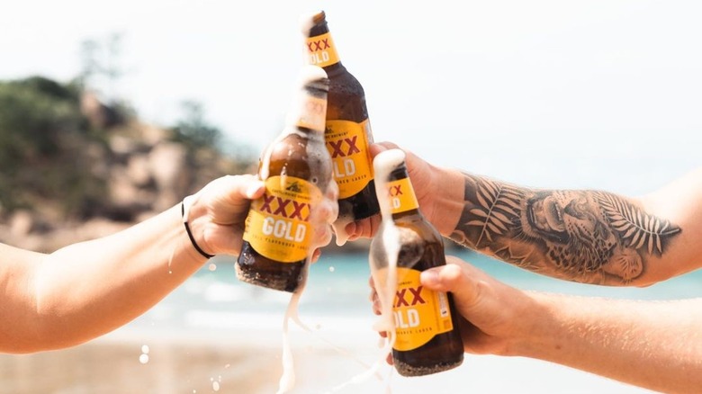 hands clinking bottles of XXXX Gold