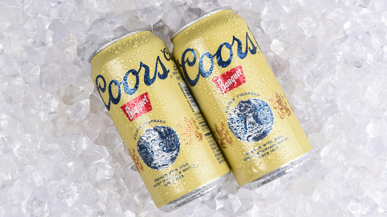 Two cans of Coors Banquet resting in ice.