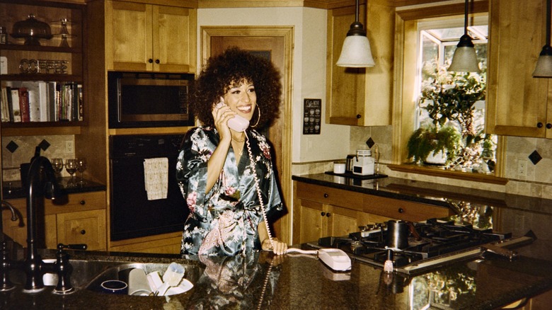 woman with a landline phone in an '80s-styled kitchen