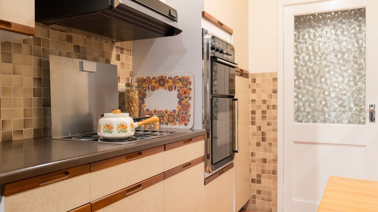 1970s-styled kitchen with wall oven and frosted glass door