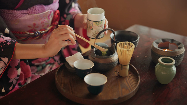 A woman in a kimono preparing matcha tea for a traditional Japanese tea ceremony
