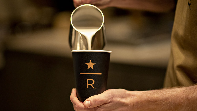Person filling cup with Starbucks reserve logo 