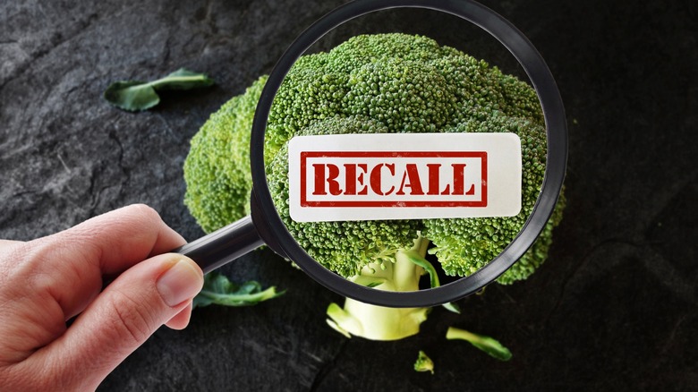 Person holding magnifying glass up to broccoli with "recall" spelled out