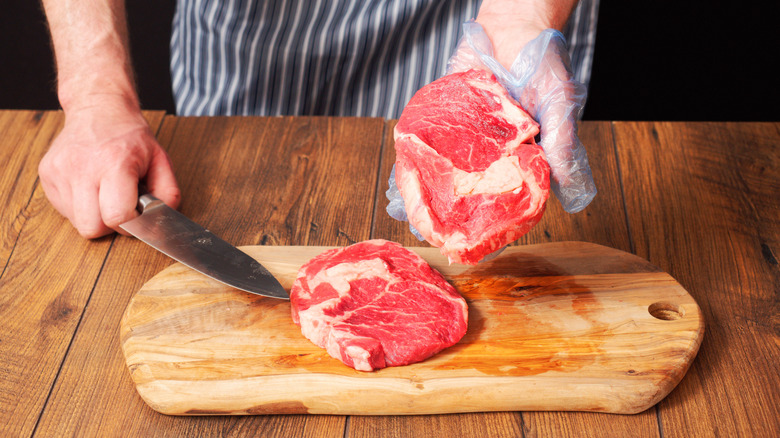 A butcher holding up a slice of beef