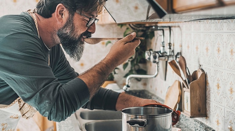 Person tasting dish in kitchen