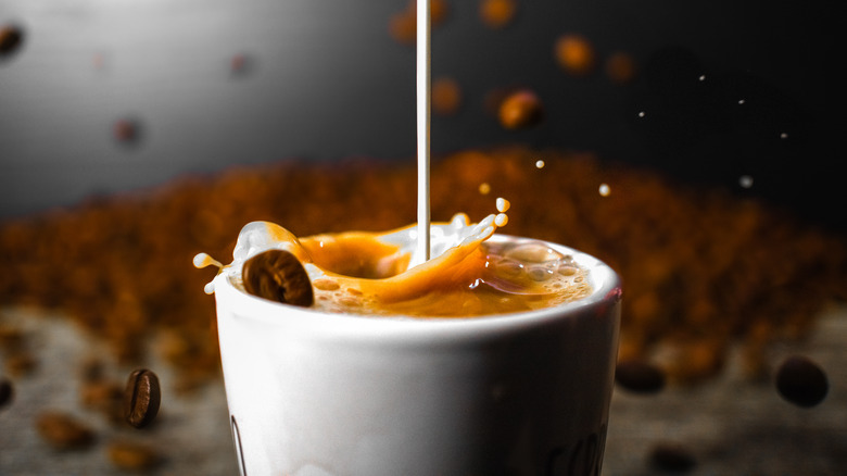 Coffee creamer being poured into a cup of coffee