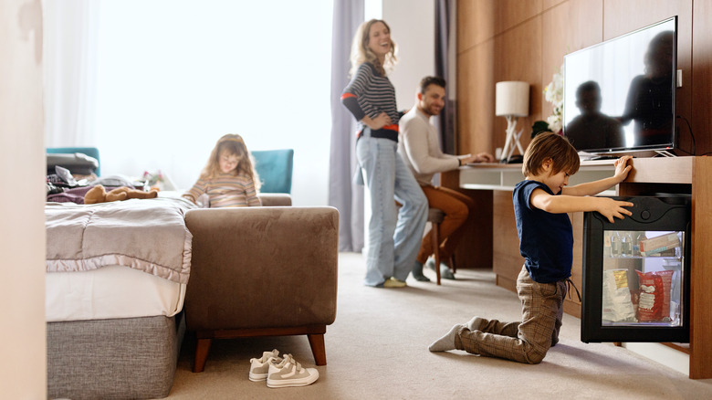 Family in hotel room, child opening fridge