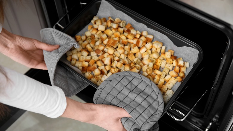 hands putting a tray in the oven