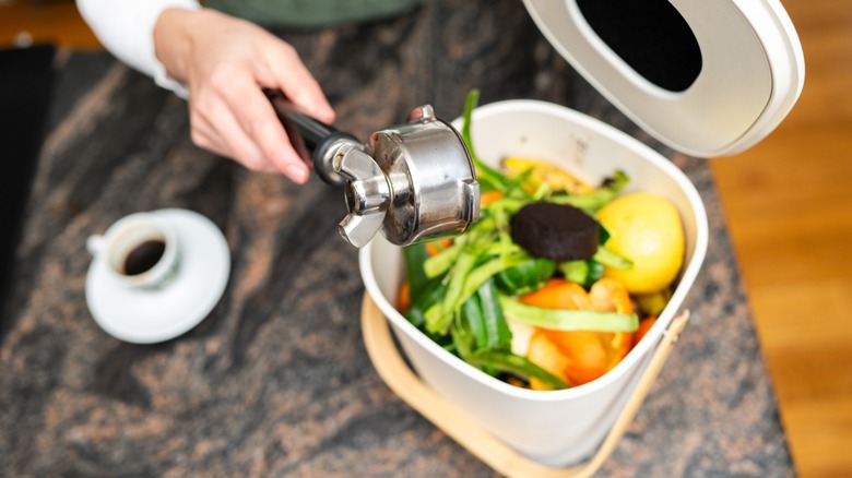 hands scoop coffee grounds into home compost bin