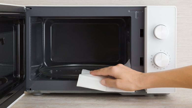 hand with paper towel in open microwave