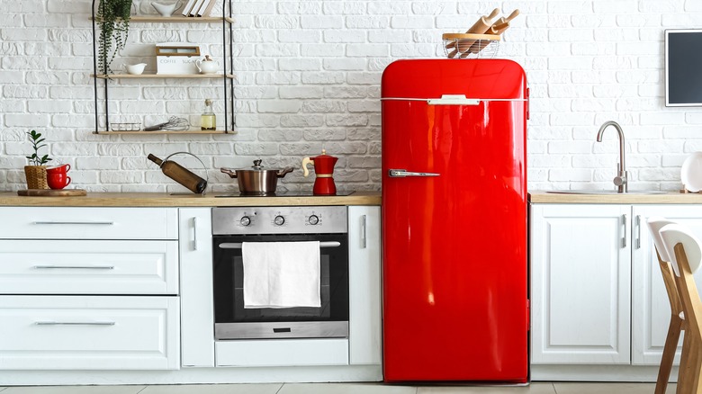 Kitchen interior with white cabinets, silver and black oven, and red fridge
