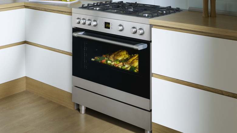 Silver and black oven in kitchen with white and wood-tone cabinets